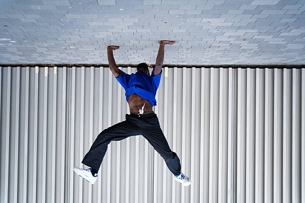 Athletic male performing dynamic jump, leaping high with powerful muscular physique near contemporary architectural setting