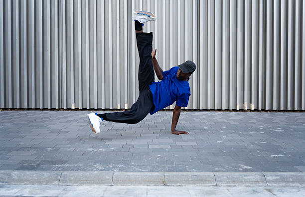 istock Young man breakdancing outdoors, skillfully balancing on one hand while raising his legs high, showcasing impressive strength and flexibility 2234019491