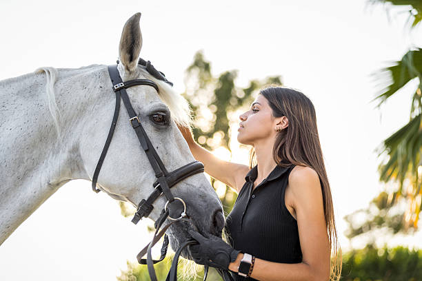 istock Young Spanish woman caring for her white horse during a training session at sunset, gently caressing the animal and gazing into its eyes, embodying a deep connection and trust 2234024120