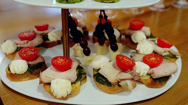 istock Elegant two tiered serving tray displaying miniature appetizers with pesto, roasted pork, cherry tomatoes, and mozzarella, highlighting gourmet catering presentation 2234026292