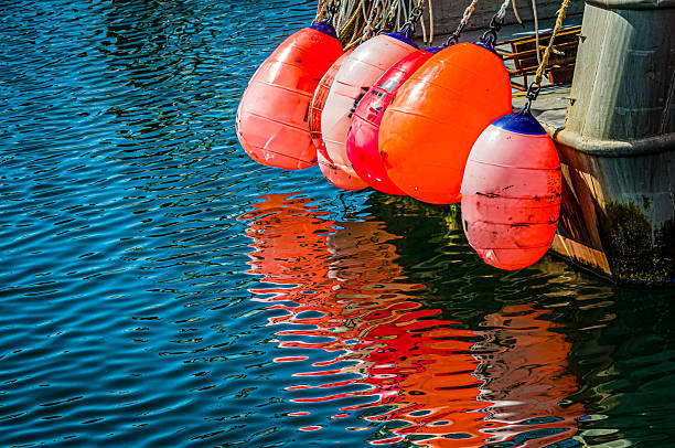 Colorful fishing buoys hang from a trawler stern and cast an abstract design onto the waters of Sandwich Marina on Cape Cod