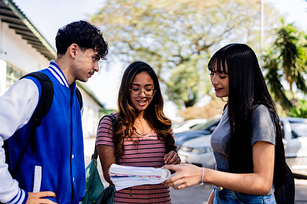 istock Teenage students looking at an open notebook and discussing schoolwork outside school 2234028826