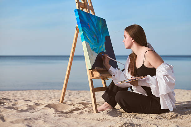 istock Female painter creating art on canvas by seaside 2234029244