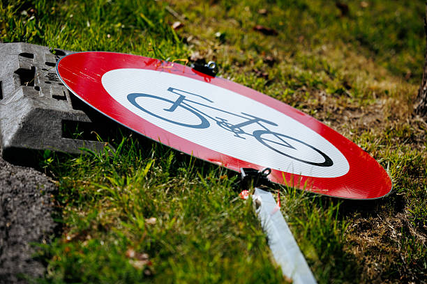 Fallen bicycle road sign on grass near pavement, lifestyle