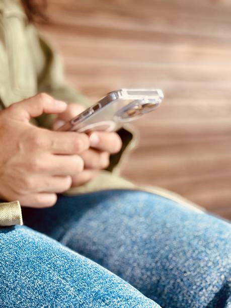 istock Using a smartphone on a bench connects users to digital content and communication. A person sits comfortably on a wooden bench, engaged with their smartphone, highlighting modern techs influence 2234047724