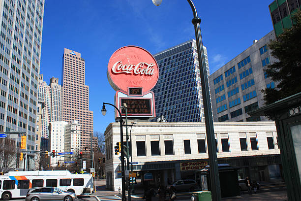 View of the skyscraper skyline of Peachtree Center with iconic Coca-Cola red round sign dominating the foreground as seen looking up Peachtree Street in Atlanta, Georgia.