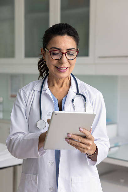 istock Smiling middle-aged female doctor working on tablet device 2234052245