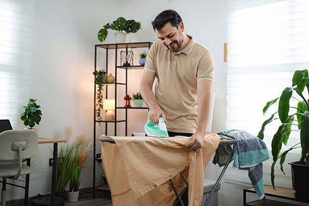 istock Man smiling while ironing clothes at home 2234053037