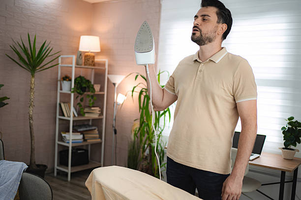 istock Man checking temperature of iron while ironing clothes at home 2234053130