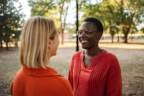 istock Two young women smiling and talking in a park 2234054400