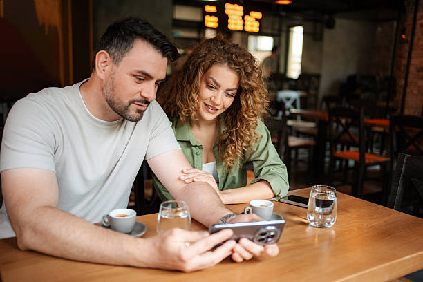 istock Couple looking at smartphone and drinking coffee in cafe 2234056161