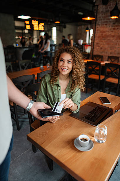 istock Young woman paying with credit card using NFC technology in a cafe 2234056278