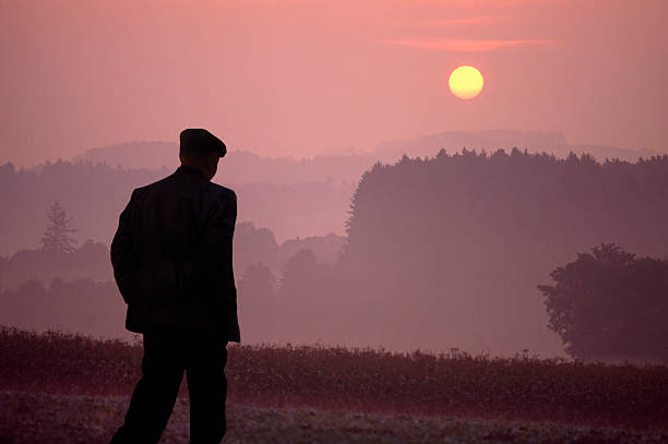 Germany Bavaria, Munich countryside, farmer walking at sunrise.