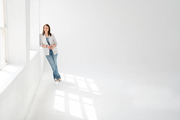 istock Businesswoman leaning against wall in empty office room 2234067818