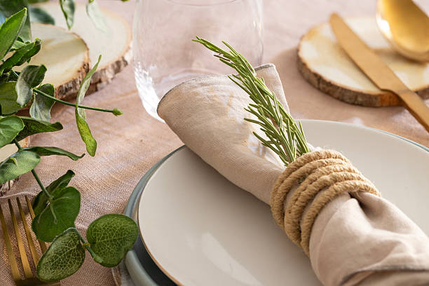 Modern rustic estive table setting decor with artesian plate , gold cutlery, linen napkin decorated with rosemary,