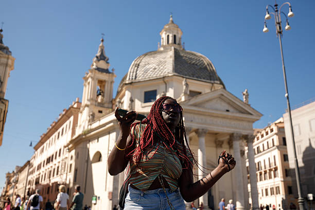Young woman dancing joyfully while listening to music on her phone at Piazza del Popolo in Rome.
