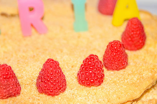 A dessert topped with fresh raspberries and colorful letters spelling out a celebratory message.