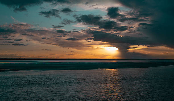 istock Sunset over tranquil waters with dramatic clouds in the evening sky 2234068316