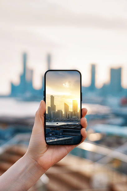 istock Hand holding smartphone capturing cityscape with sunset in background 2234075408