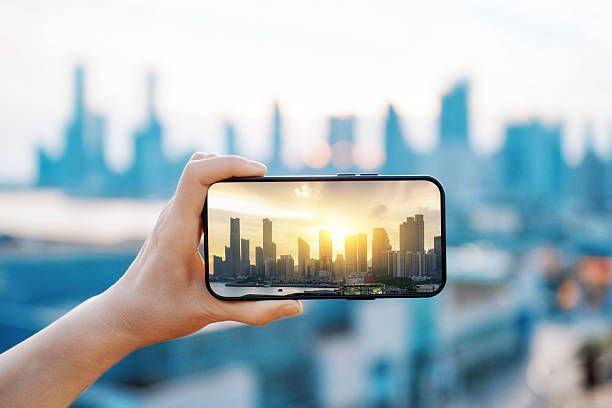 istock Hand holding smartphone capturing cityscape with sunset view 2234076876