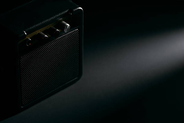 Small black guitar amplifier in spotlight with dark background.