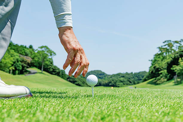 istock Hands placing a golf ball on a tee on a teeing ground with fresh greenery 2234082482