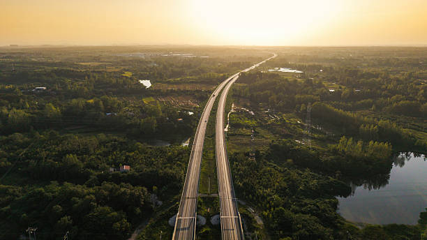 istock Aerial View of Highway at Sunset Surrounded by Greenery 2234085081