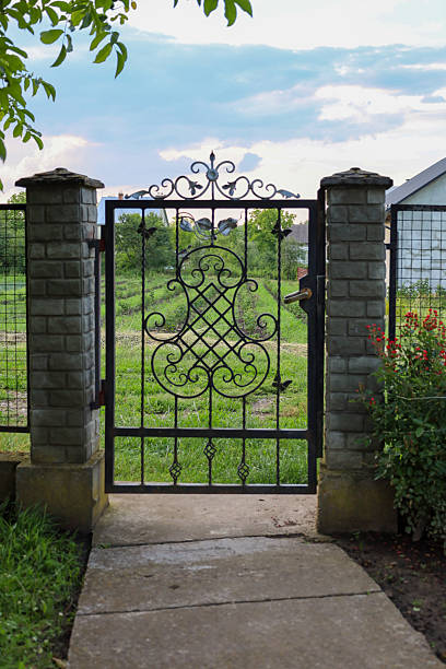 istock A wrought-iron gate with decorative elements leads to a green garden. It’s a perfect blend of art and functionality. The gate harmoniously blends into the rural landscape. 2234090037