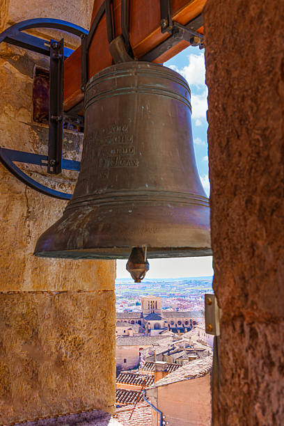 Large bronze bell hanging in the bell tower , framing the cityscape of cuenca cathedral and blue sky