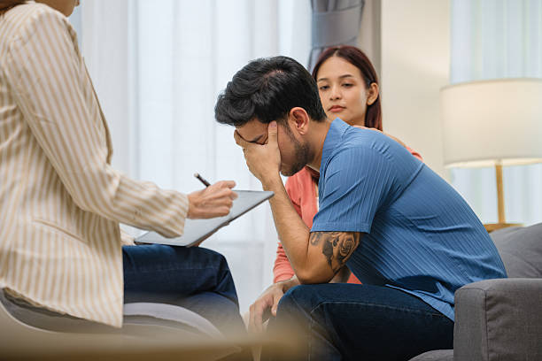 istock distressed man covers his face with his hands during a couple's therapy session 2234097457