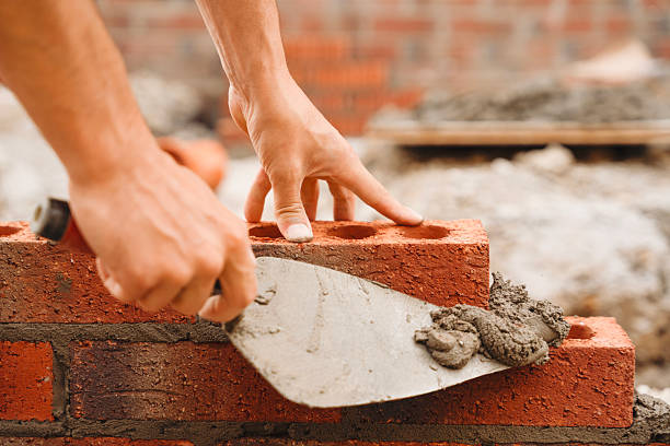 istock Construction worker laying bricks with mortar at a building site during daylight hours in a developing urban area 2234102418