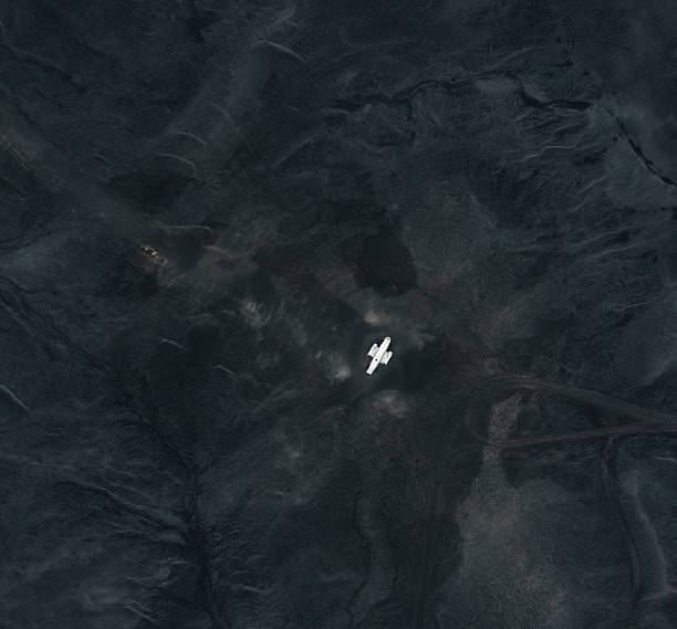 Aerial view of a desert highway with two cars driving on it. The landscape is arid and barren, emphasizing isolation and adventure. The visual style conveys a sense of vastness and solitude. Potential usage includes travel, exploration, or road trip themes.