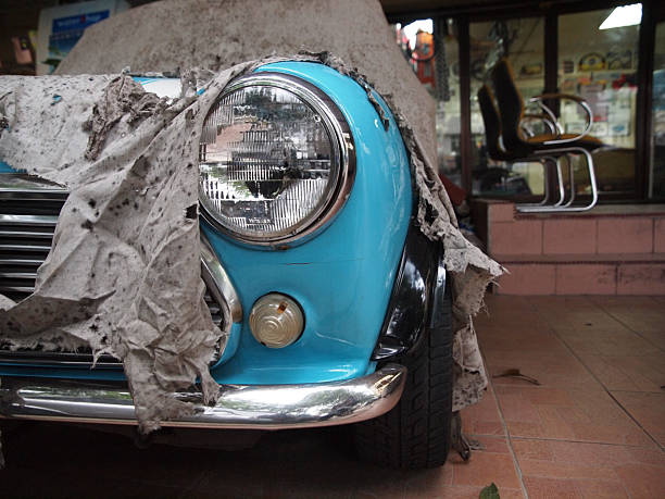 A blue classic car wrapped or covered in a torn cloth.