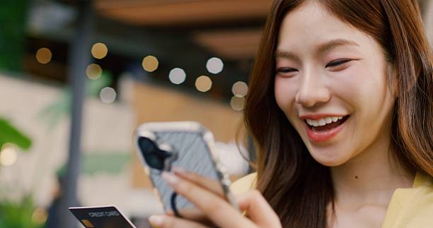 istock Happy woman using smartphone to pay with credit card 2234106558