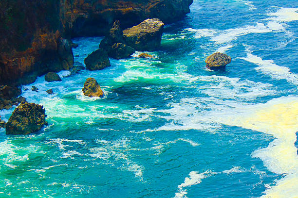 A landscape view of the blue sea water and the rocky cliffs in the ocean.