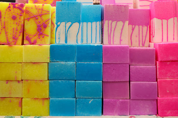 A vibrant display of handmade soap bars in striking shades of yellow, blue, pink, and purple. Perfectly stacked, these artisan soaps showcase their colorful patterns and textures, symbolizing eco-friendly skincare, wellness, and natural beauty products.