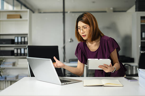 istock Business women hand working with tablet and laptop computer with documents on office desk in modern office. 2234108585