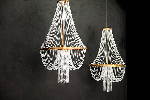 Elegant crystal chandeliers hanging against dark textured background in luxurious setting.