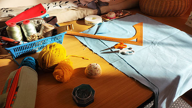 A variety of fabrics, colorful threads, scissors, and pins are laid out on a rustic wooden surface, highlighting the tools of a home sewing enthusiast