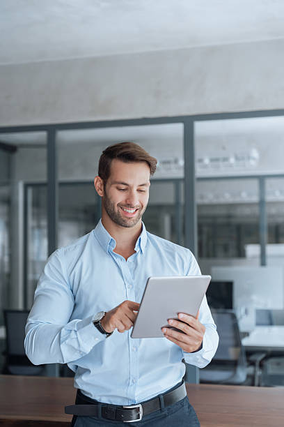 istock European smiling young businessman entrepreneur working on touchscreen computer device. Latin hispanic ceo business man ceo manager using tablet pad computer in office, looking at screen. Vertical 2234112792