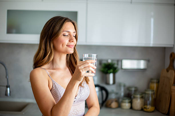 istock Young woman enjoying fresh water in the kitchen 2234114619