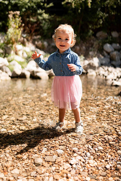 Adorable child splashing and having fun in natural spring water on hillside.