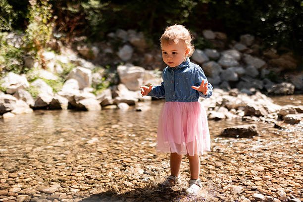 Adorable child splashing and having fun in natural spring water on hillside.