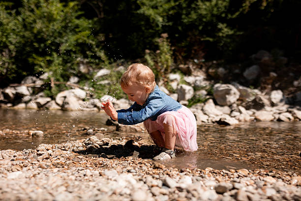 Young girl enjoying refreshing spring water in hills, childhood and nature concept.
