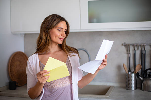 istock Woman reading a letter in the kitchen at home 2234114818