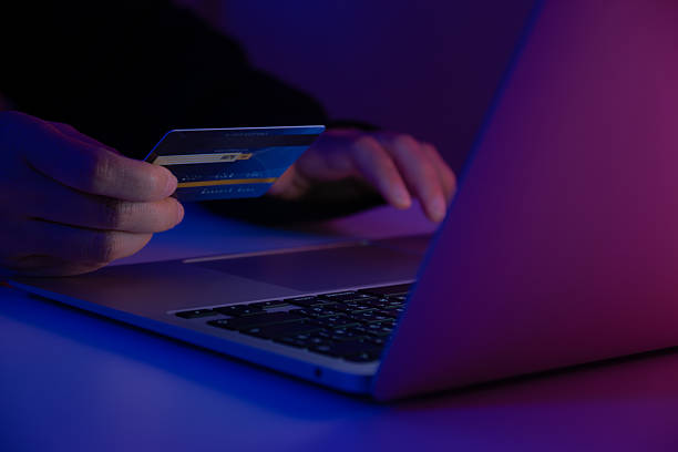 istock Hacker holding a credit card while accessing a system with a laptop. Concept of cybercrime, online fraud, identity theft, hacking, and digital security risk 2234116450