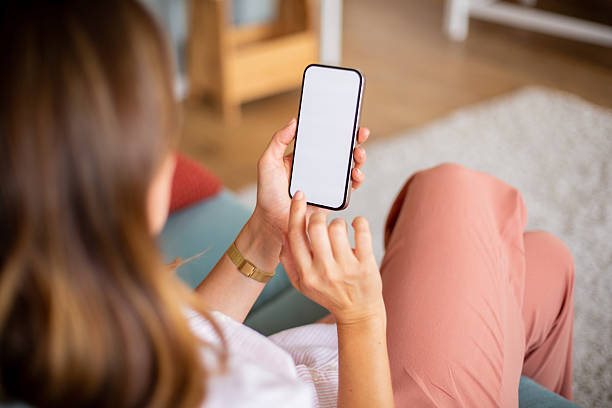 Woman relaxing on sofa using smartphone with blank screen