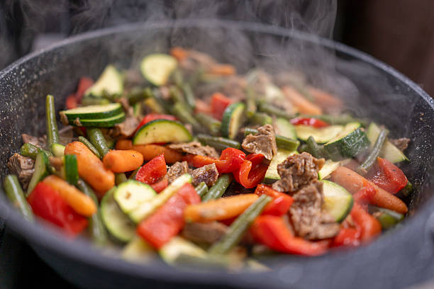 Colorful mix of fresh zucchini, green beans, red peppers, and carrots stir-fried with tender beef, served in a steaming rustic skillet.