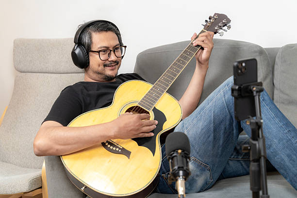 istock Young man live streaming guitar performance on smartphone at home 2234118805