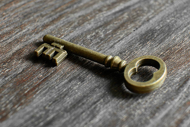 istock Old brass key resting on wooden surface 2234119691